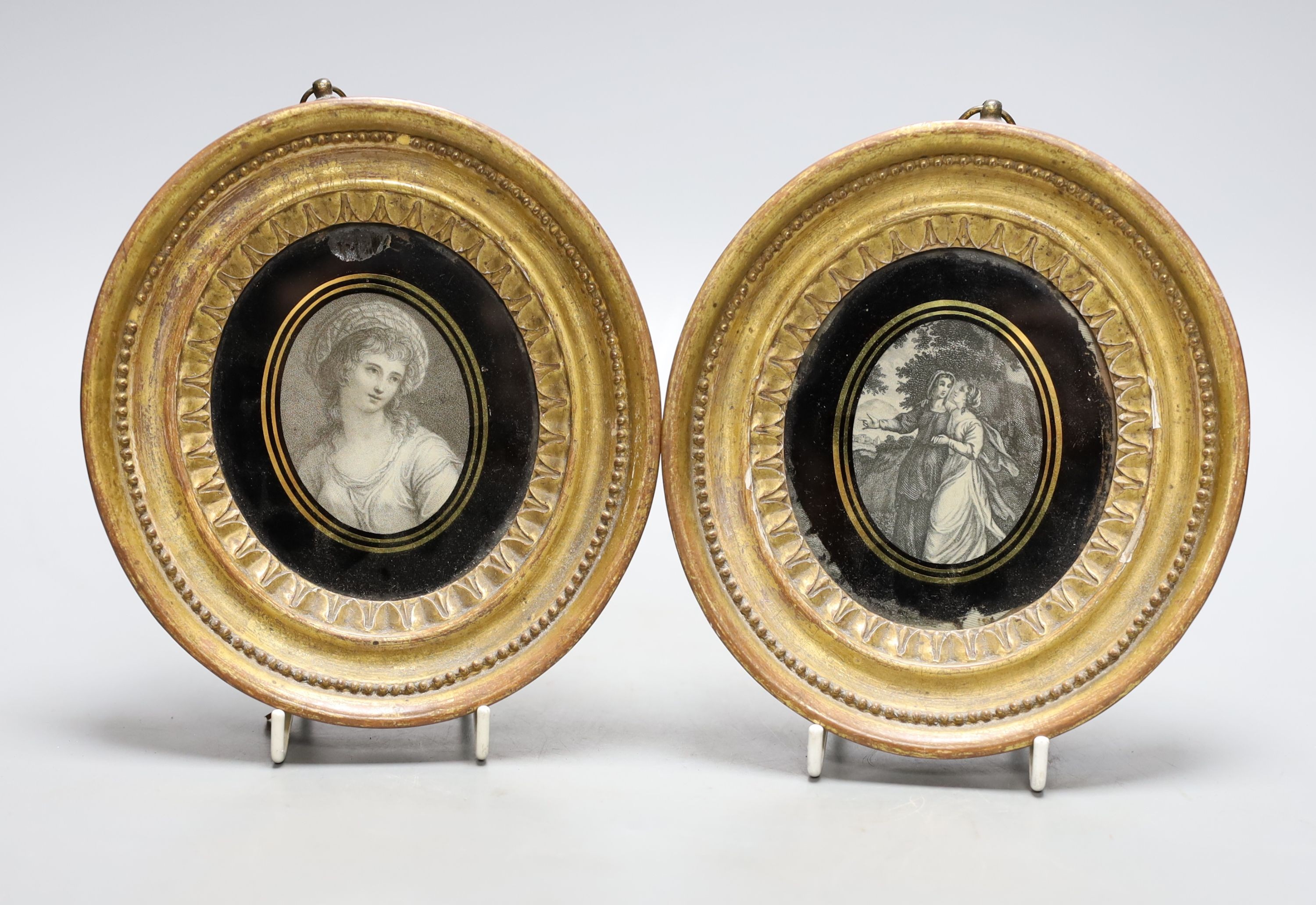 A pair of 19th century oval gilt frames, 6.5cm. high, with inset monochrome prints